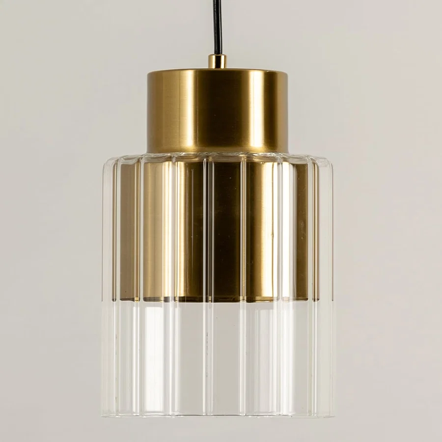Gold metal pendant light with clear glass shade illuminated to display elegant modern ceiling lighting design.