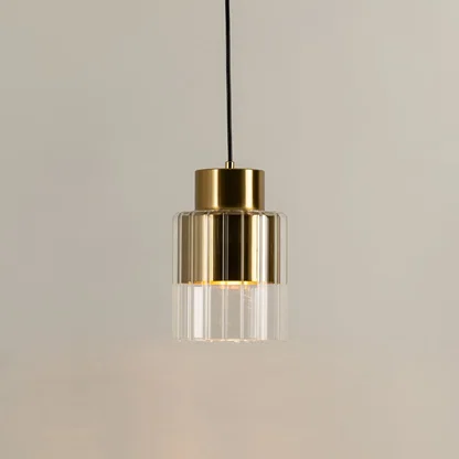 Gold metal pendant light with clear glass diffuser illuminated to highlight premium modern decorative lighting.