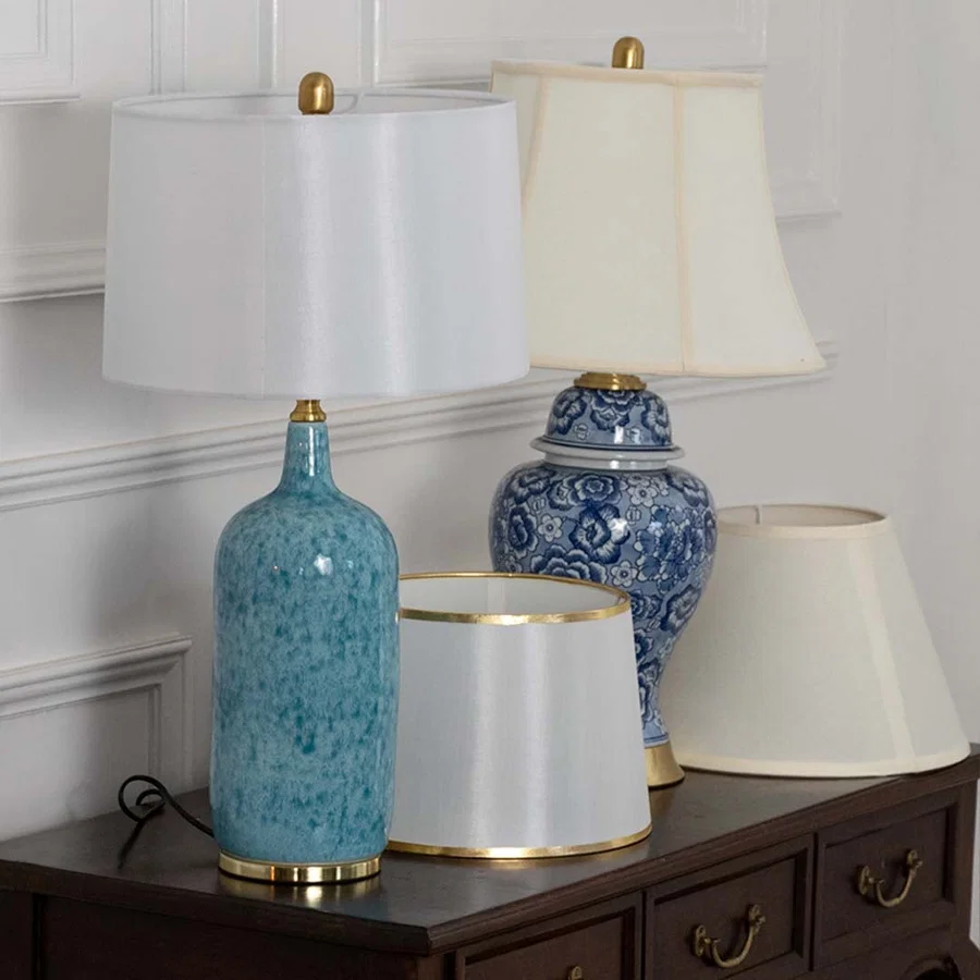 Table lamps light off with blue ceramic bases and white fabric shades placed on a dark wooden console for elegant home styling.
