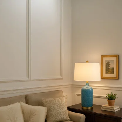 Modern blue ceramic table lamp with gold metal base and white fabric shade adds elegance and a refreshing coastal charm to interiors.