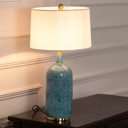 Turquoise ceramic table lamp with fabric shade placed on a wooden console table offering warm classic decor lighting.