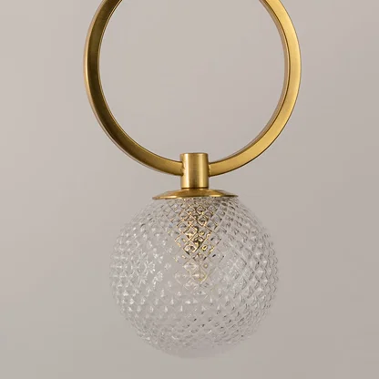 Gold metal wall light closeup highlighting textured glass globe detailing and premium lighting craftsmanship quality.