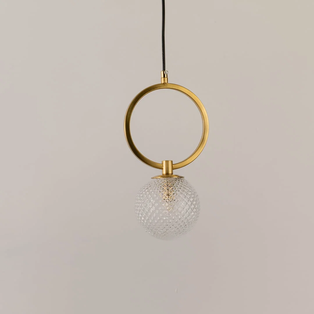 Gold metal wall light with textured glass globe illuminated to display elegant contemporary decorative lighting appeal.