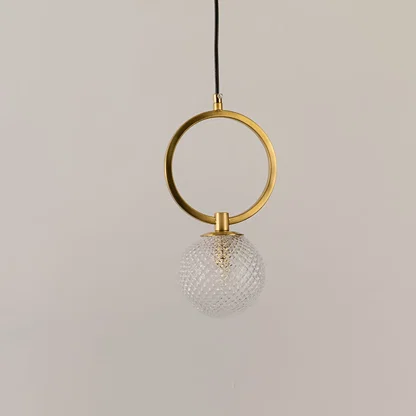 Gold metal wall light with textured glass globe illuminated to display elegant contemporary decorative lighting appeal.