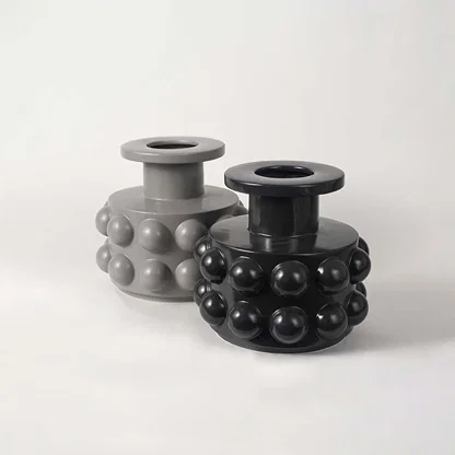 Set of two black ceramic vases with raised circular textures arranged in a modern living space setup.
