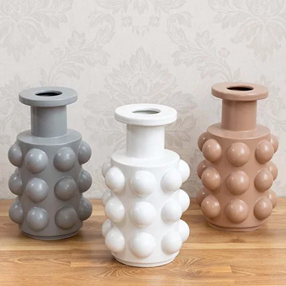 A beige designer vase with sphere accents shown as part of a styled grouped decor setup highlighting its modern statement design for interiors.