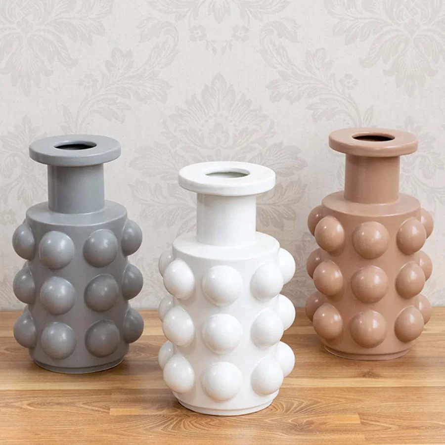A beige designer vase with sphere accents shown as part of a styled grouped decor setup highlighting its modern statement design for interiors.