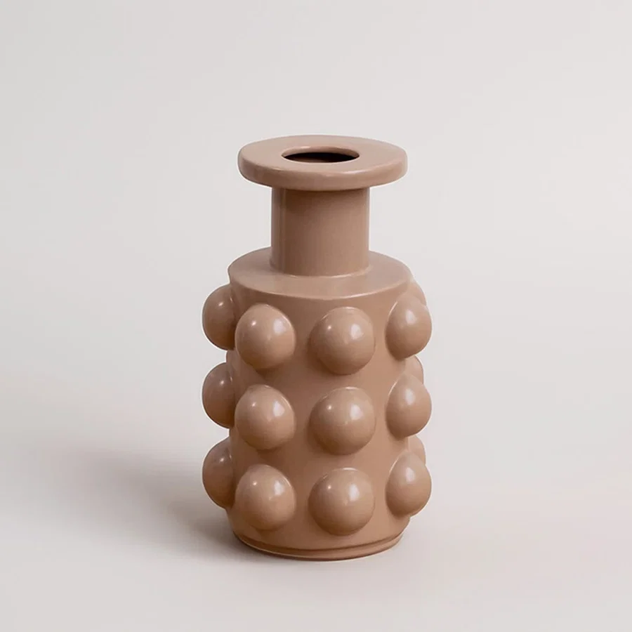 A beige contemporary vase featuring raised circular forms presented on a simple white background offering a clean minimal decorative look.