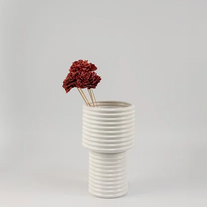 Red sola flower sticks arranged in a modern ceramic vase with artificial decorative flowers for stylish home and office decor.