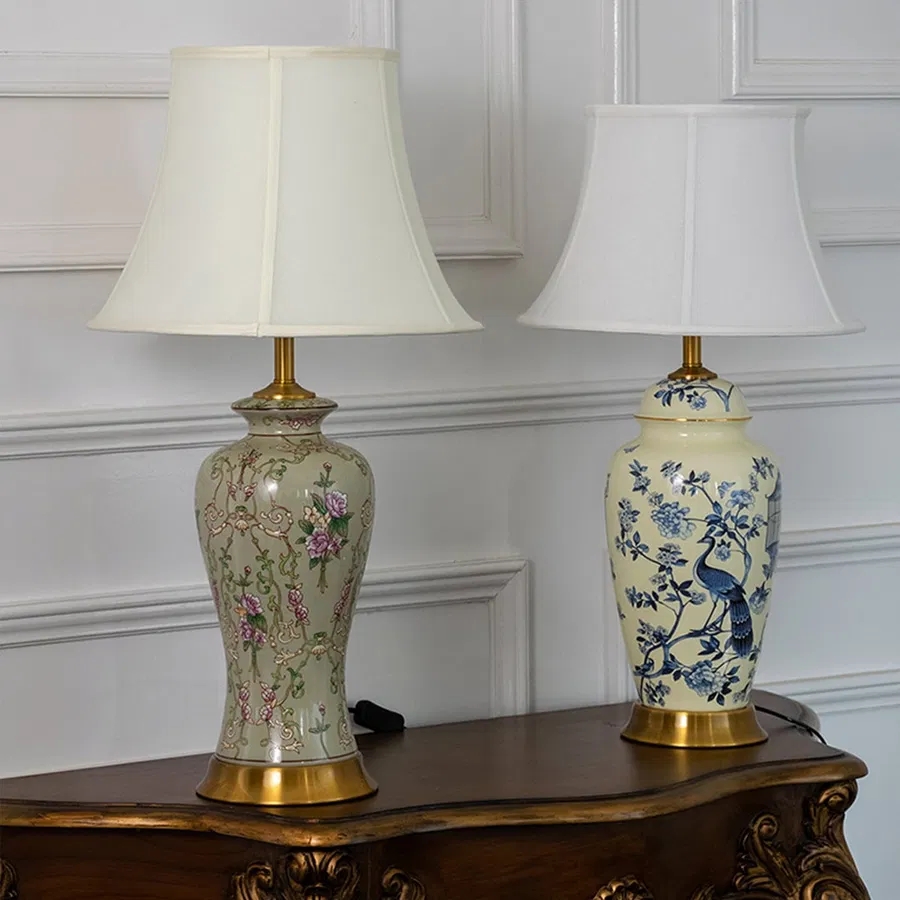 Pair of ceramic table lamps with floral motifs and golden bases styled together as elegant decorative interior accents.