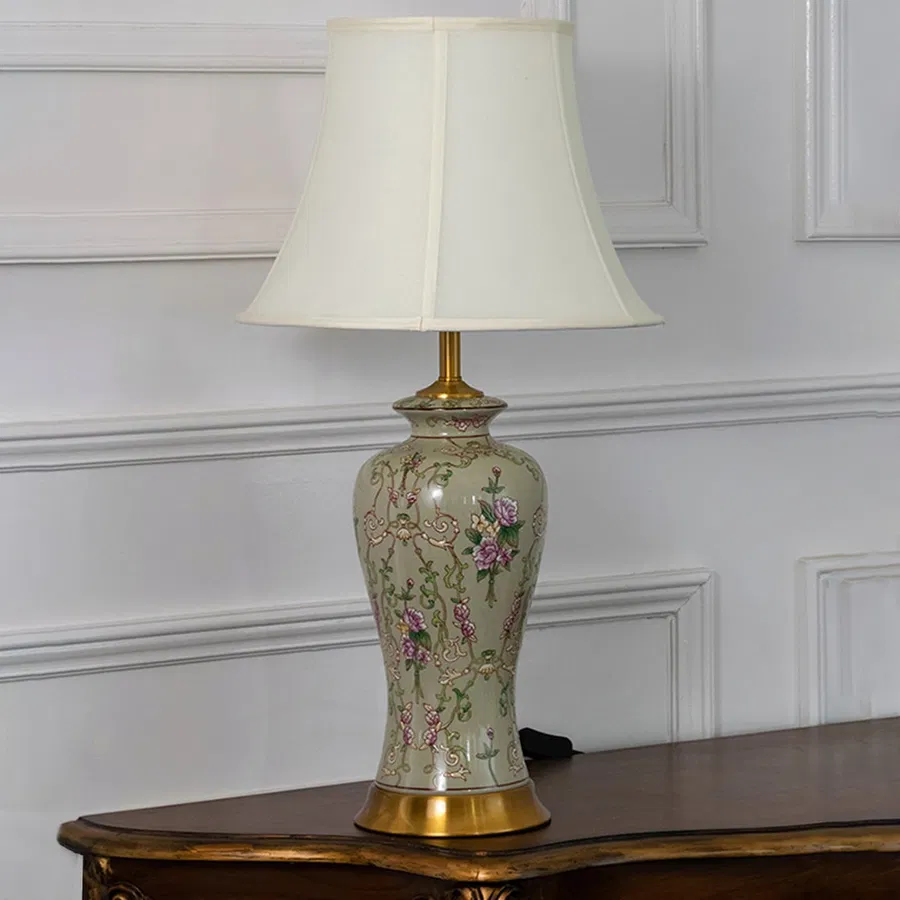 Classic ceramic lamp with hand painted floral motifs and golden base displayed with light off against white background.