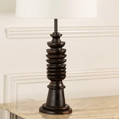 Turned wood lamp base with rich dark finish and bronze accents showcasing classic craftsmanship and decorative appeal.