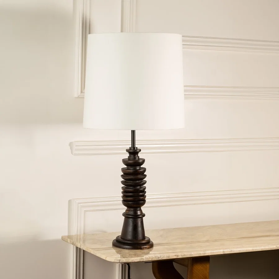 White fabric shade table lamp with turned wood base and bronze accents for elegant bedside and living room decor.