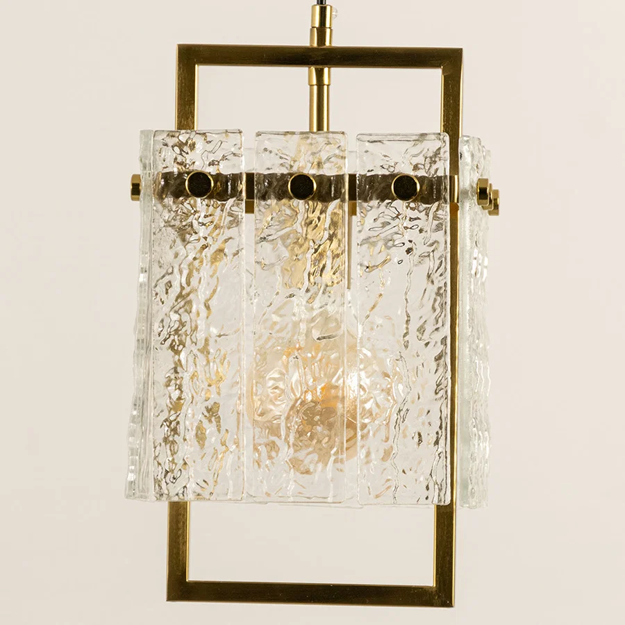 Gold metal wall light with textured glass shade emitting warm glow perfect for modern interior wall decor styling.