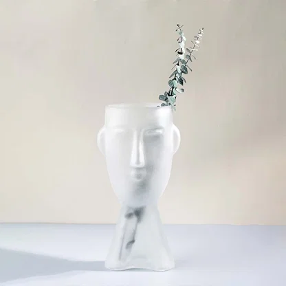 Frosted glass vase in abstract face design tall artistic decor piece matte white finish light on white background for home interiors.