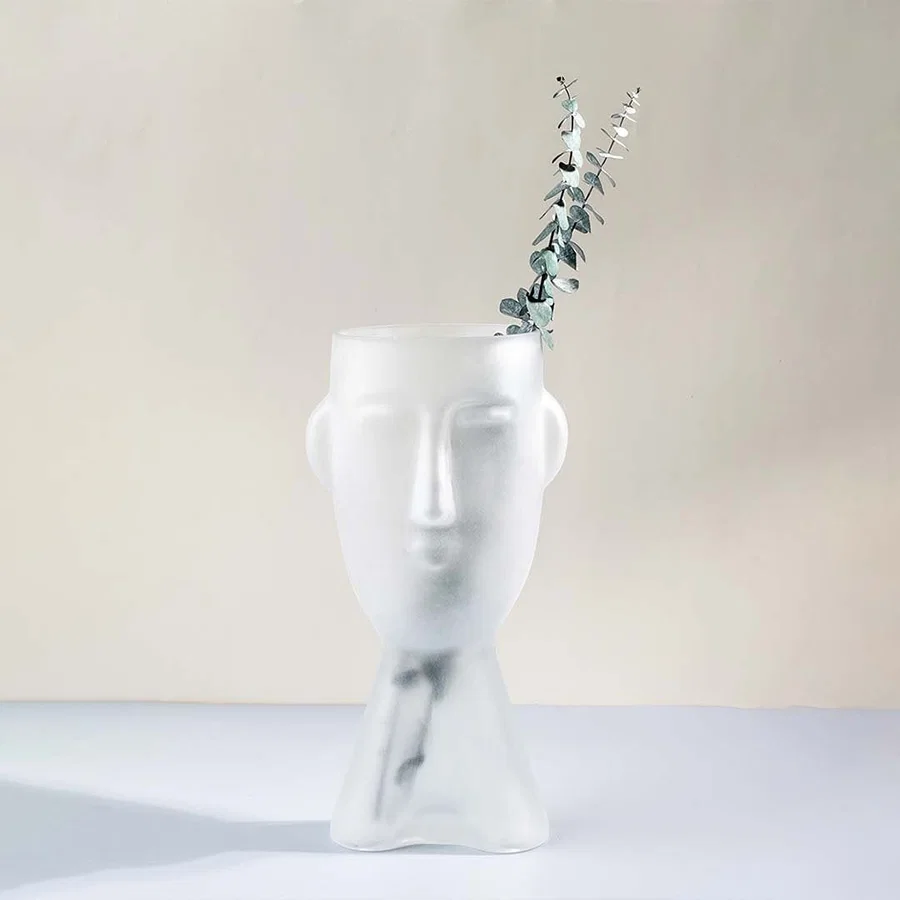 Frosted glass vase in abstract face design tall artistic decor piece matte white finish light on white background for home interiors.