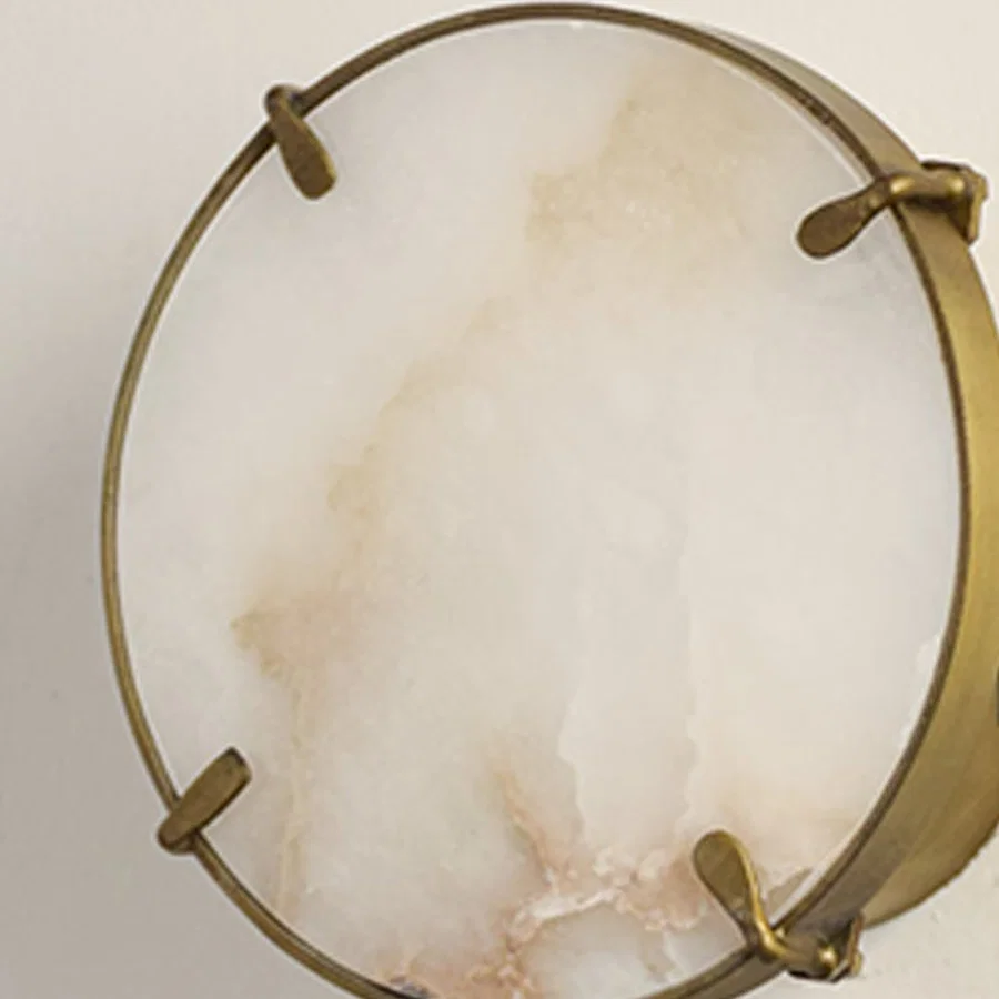 Closeup of white marble and gold metal wall light for premium bedroom and modern decor styling spaces.