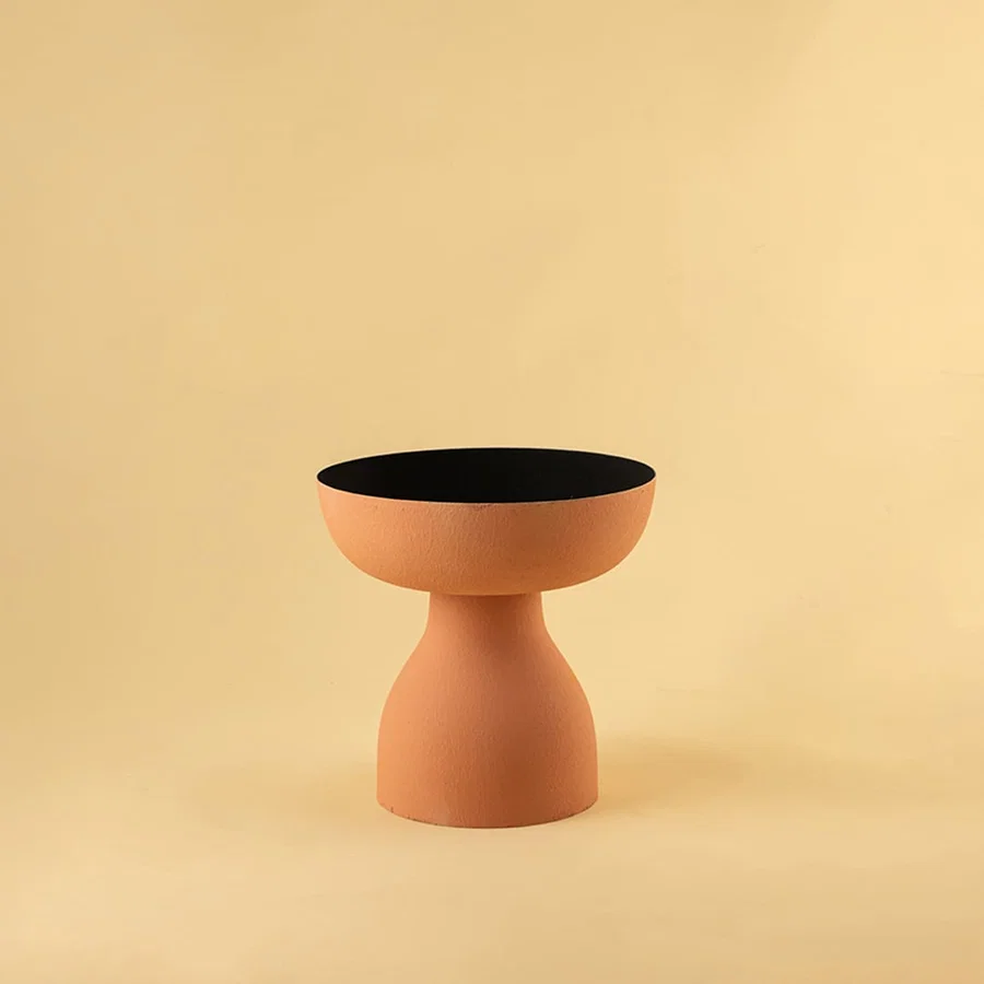 Terracotta orange pedestal bowl with matte finish and black interior displayed on a clean white background for modern decor styling.