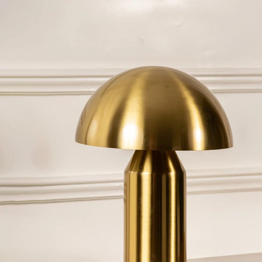 Closeup of gold metal dome table lamp featuring a polished rounded shade and smooth cylindrical base highlighting its modern craftsmanship.