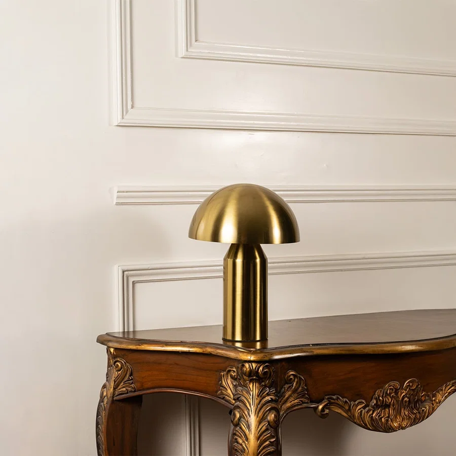 Gold metal mushroom table lamp with dome shade and cylindrical base designed for contemporary decorative table lighting.