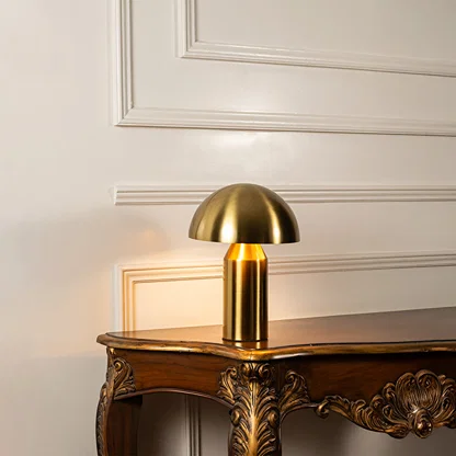 Gold metal mushroom table lamp displayed on a carved wooden console table creating elegant modern task lighting.