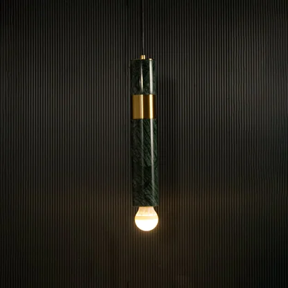 Green marble and metal cylinder pendant light with exposed bulb hanging against dark textured wall with light on for luxury modern décor.