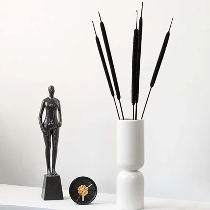 Elegant bulrush stems in a modern white vase styled with artistic decor adding natural charm to home interiors.