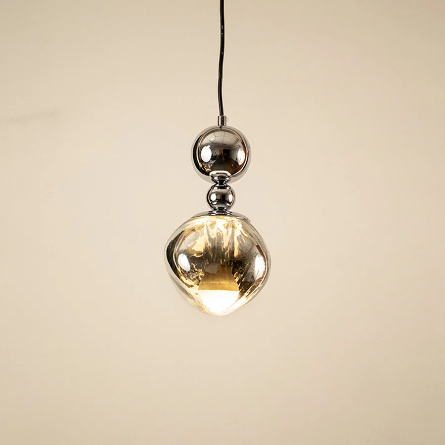Silver metal pendant light with mirrored finish illuminated to highlight modern decorative ceiling lighting design.