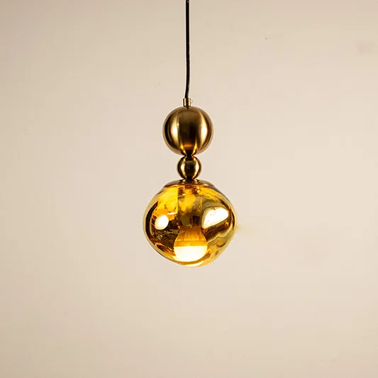 Gold metal pendant light with mirrored finish illuminated to showcase luxury ceiling lighting and modern elegance.