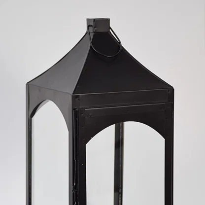 Closeup of black metal lantern with angular top and glass panels for luxury decor styling use.