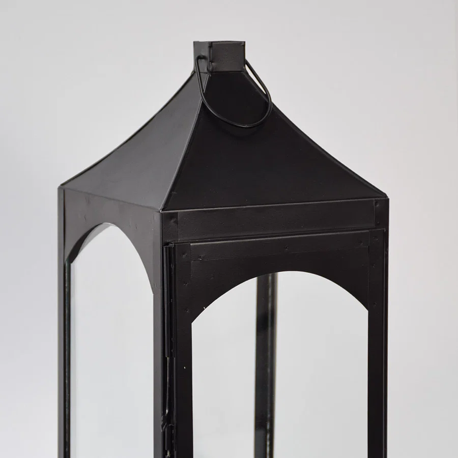Closeup of black metal lantern with angular top and glass panels for luxury decor styling use.