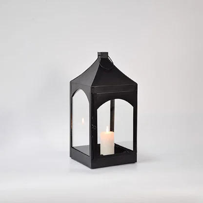 Black metal and glass lantern with candle unlit on white background highlighting solid frame clean edges and modern lantern design.