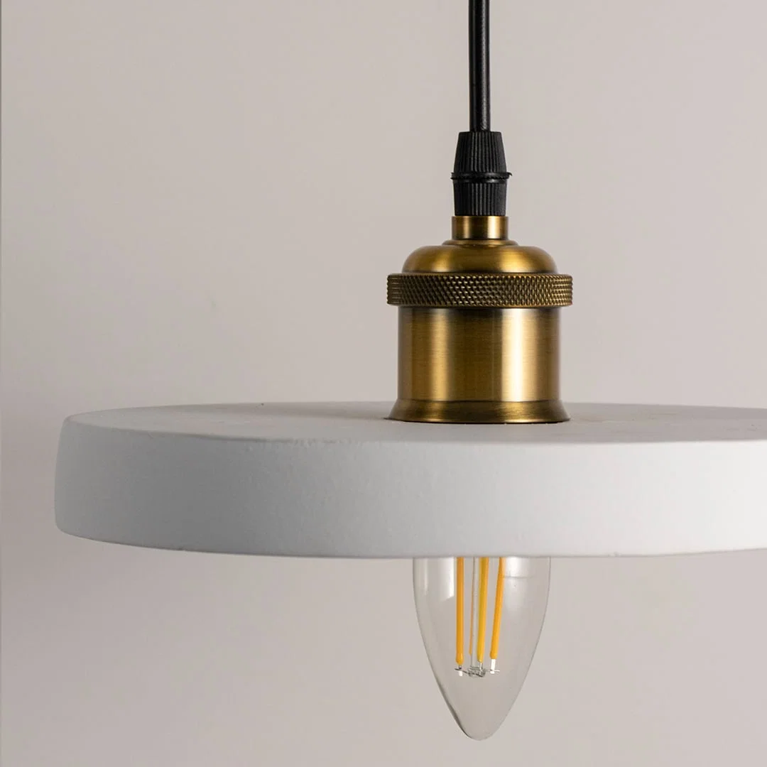 Detailed view of black metal pendant light with exposed bulb and refined gold accents.