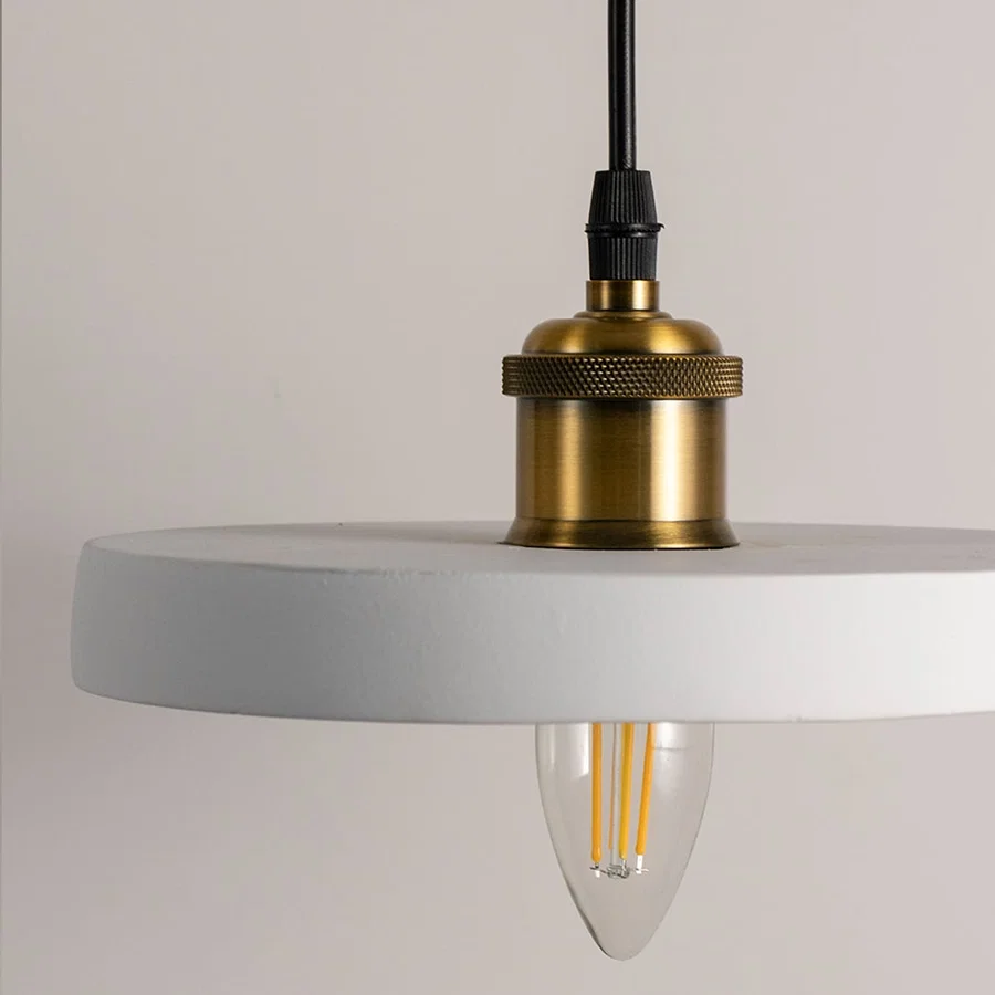 Detailed view of black metal pendant light with exposed bulb and refined gold accents.