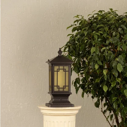 Black post light ribbed glass Light On placed next to a large green plant Lifestyle image for patio decor.