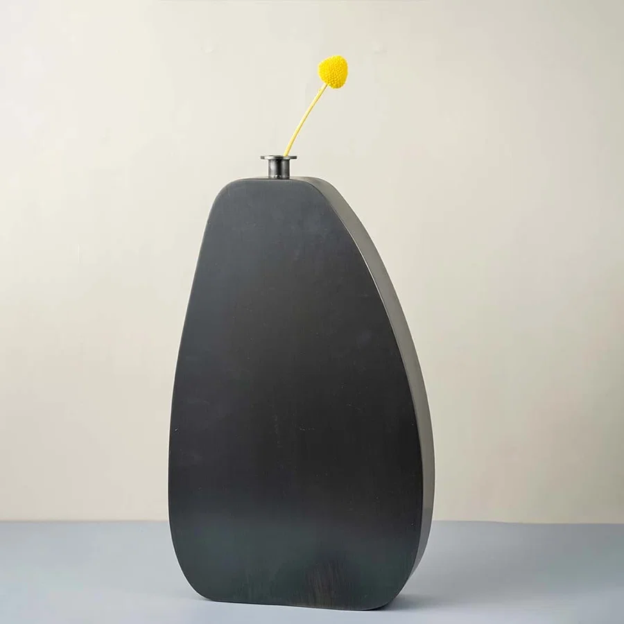 Tall black wooden vase with smooth matte finish styled with yellow flower for modern home and office decor.