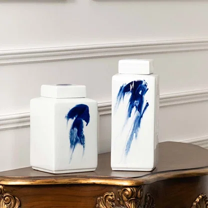 White ceramic jars with blue brushstroke artwork placed on a console for artistic modern décor styling.