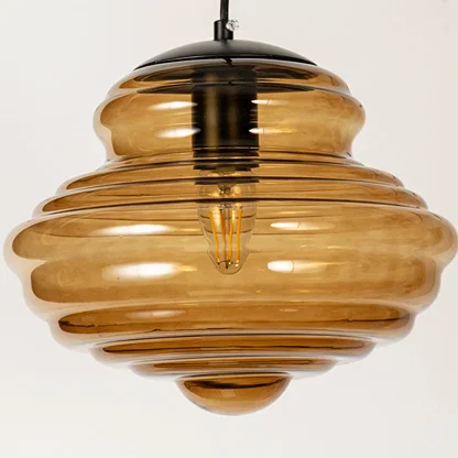 Amber ribbed glass pendant light with exposed bulb detail showcasing layered craftsmanship and modern decorative lighting.