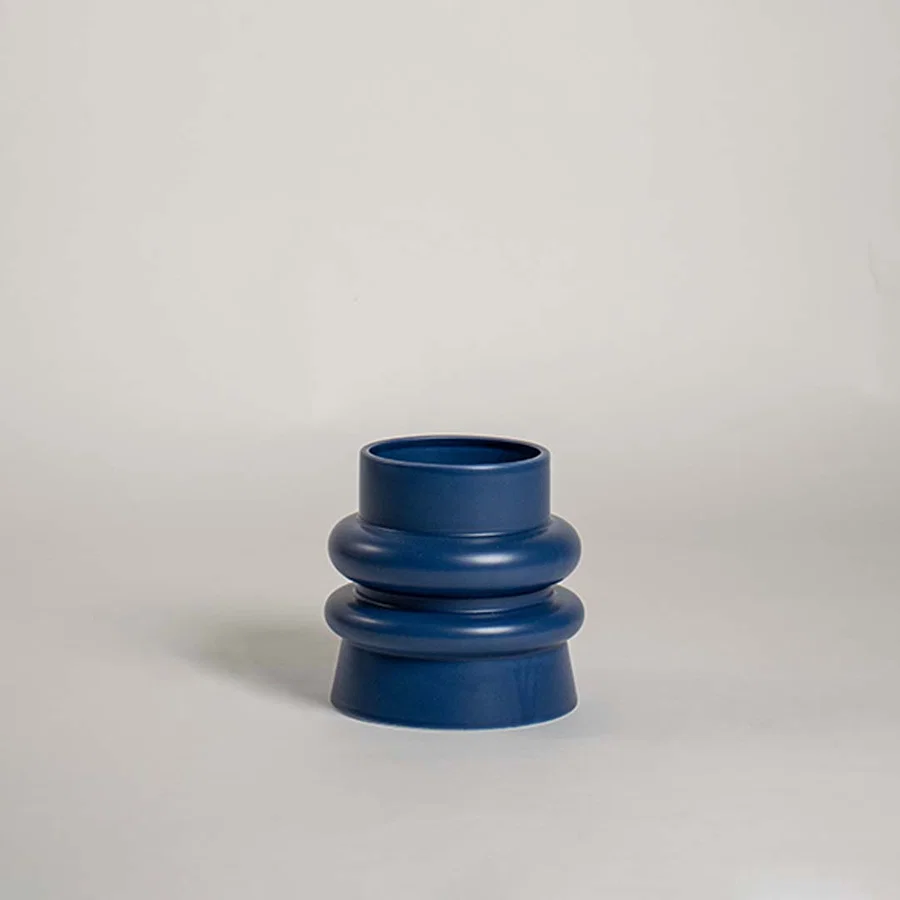 Contemporary blue ceramic vase with bold tiered design displayed against a white background showcasing its minimalist decorative style.