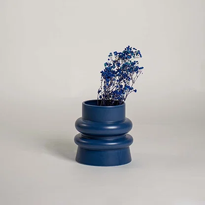 Dark navy blue ribbed ceramic vase styled with vibrant blue dried flowers on white background for striking modern decor.