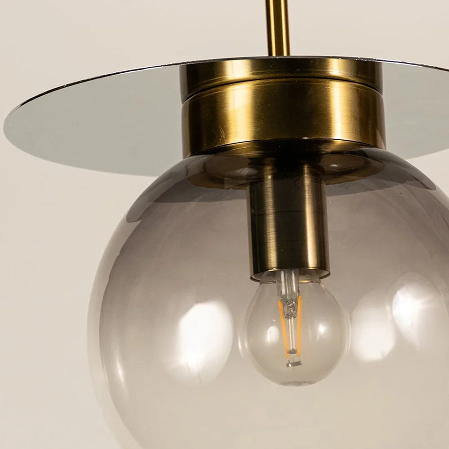 Smoked glass pendant light with metal finish and exposed bulb detail showcasing modern ceiling lighting for living spaces.