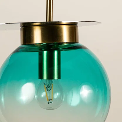 Blue glass globe pendant light featuring glossy transparent finish and brass detailing showcasing refined modern craftsmanship.