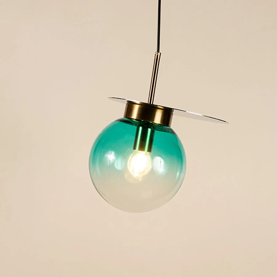 Blue glass globe pendant light with brass metal accents and decorative disc detail for elegant contemporary ceiling lighting decor.