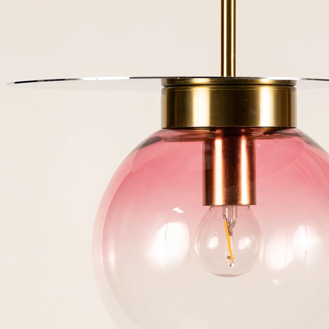 Pink smoked glass pendant light with metal finish and exposed bulb detail highlighting contemporary decorative lighting.