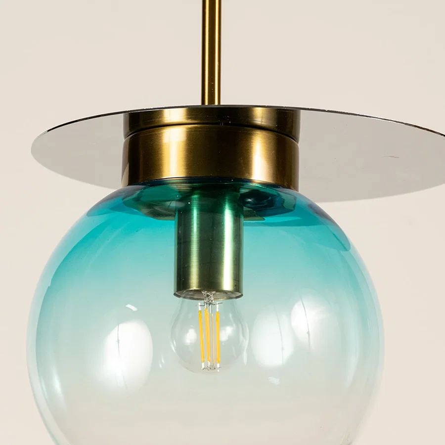 Blue glass globe pendant light featuring glossy transparent finish and brass detailing showcasing refined modern craftsmanship.