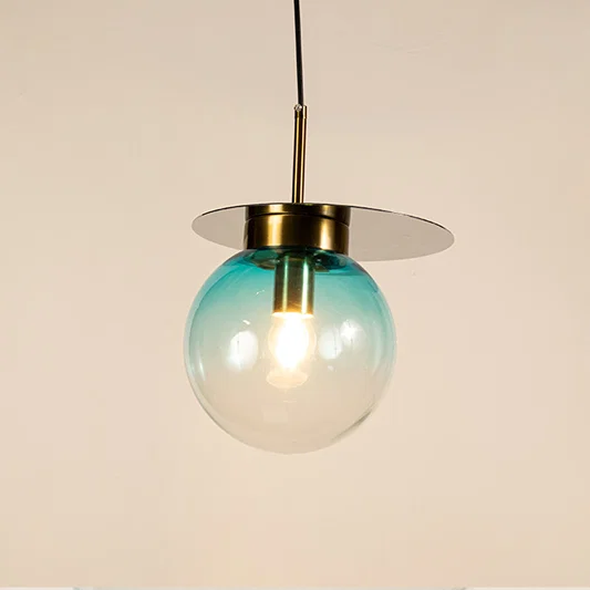 Blue glass globe pendant light with brass metal accents and decorative disc detail for elegant ceiling lighting decor.