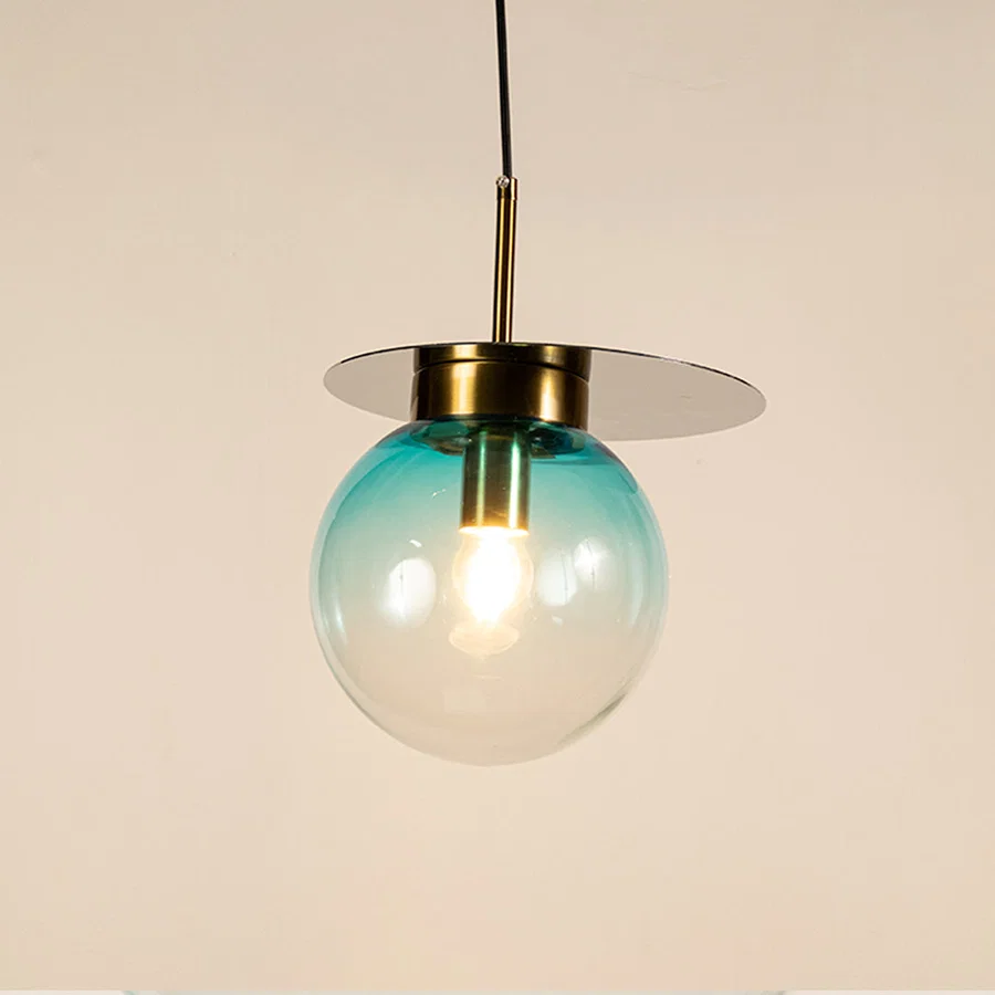 Blue glass globe pendant light with brass metal accents and decorative disc detail for elegant ceiling lighting decor.