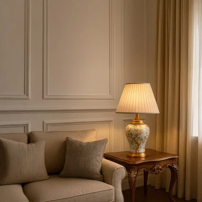 Table lamp with cream ceramic base and gold floral detailing styled on a marble table for warm elegant home decor.