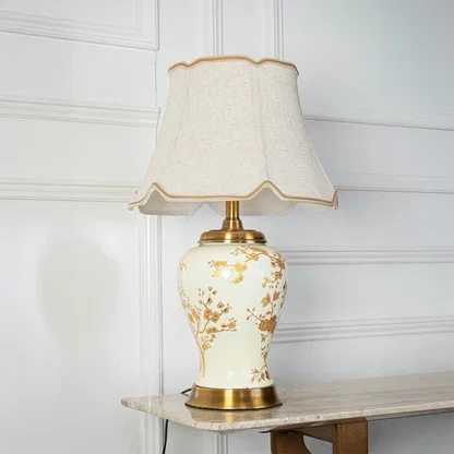 Table lamp with cream ceramic base and gold floral design displayed on a white background for clear product viewing.