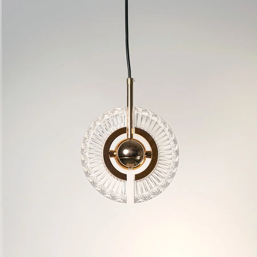 Illuminated crystal pendant light with circular gold frame casting sparkling elegant reflections.